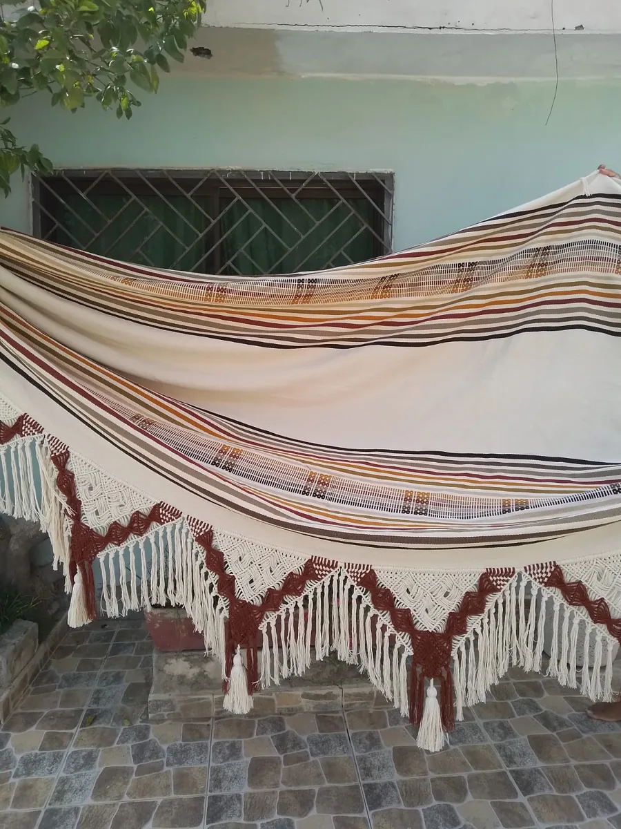 A Morroa hammock held open: cream cloth, stripes and macramé fringe.