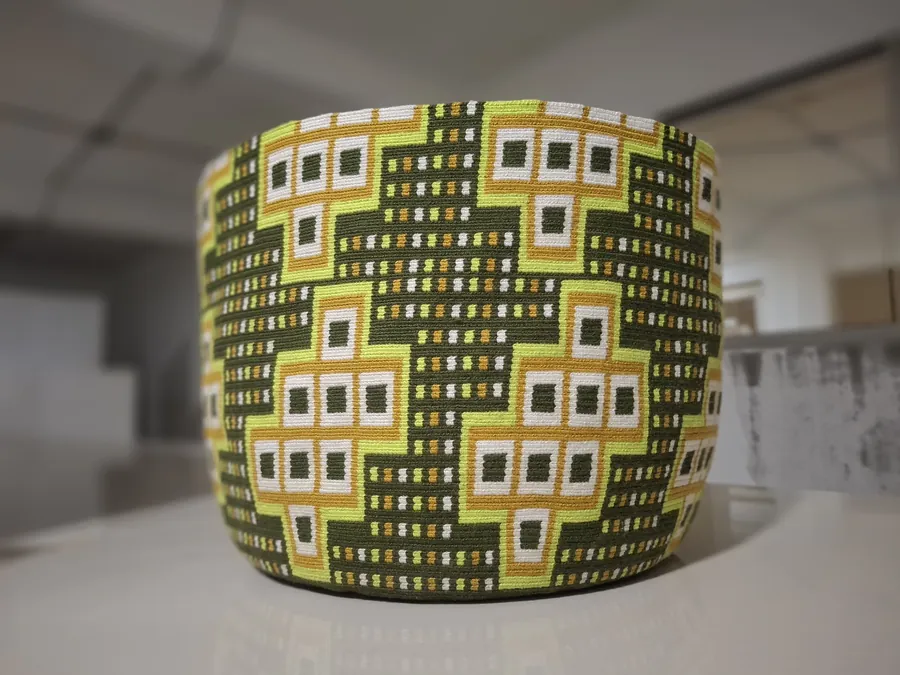 A Wayuu mochila with a geometric weave in green, white and gold.